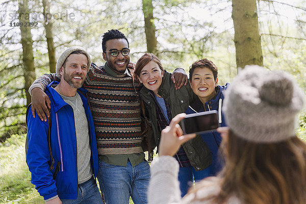 Frau mit Fotohandy fotografiert Freunde beim Wandern im Wald