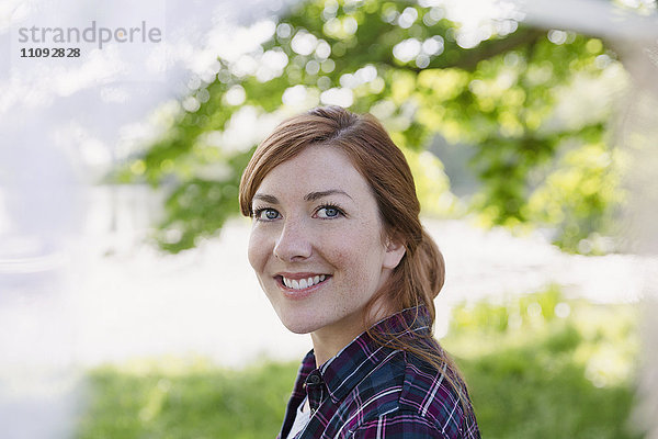Portrait lächelnde Frau mit roten Haaren im Freien