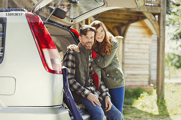 Portrait lächelndes Paar am Heck des Autos außerhalb der Kabine