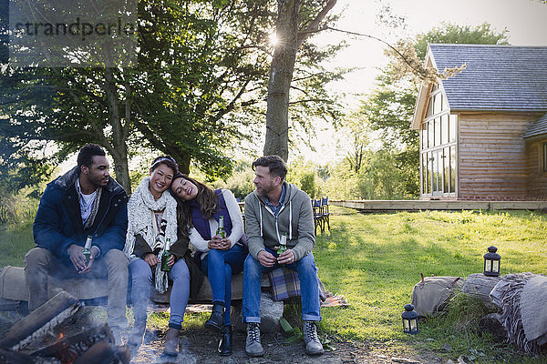 Freunde beim Biertrinken am Lagerfeuer vor der Hütte