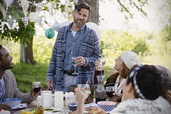 Mann toastet auf Freunde am Gartenparty-Tisch