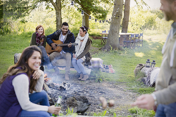 Freunde beim Gitarrespielen am Lagerfeuer