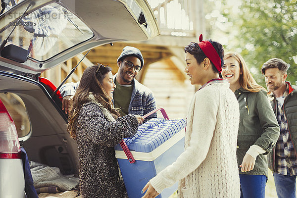 Freunde beim Entladen des Rucksacks am Heck des Autos