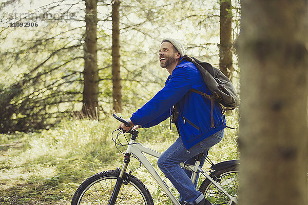 Lächelnder Mann beim Mountainbiken im Wald