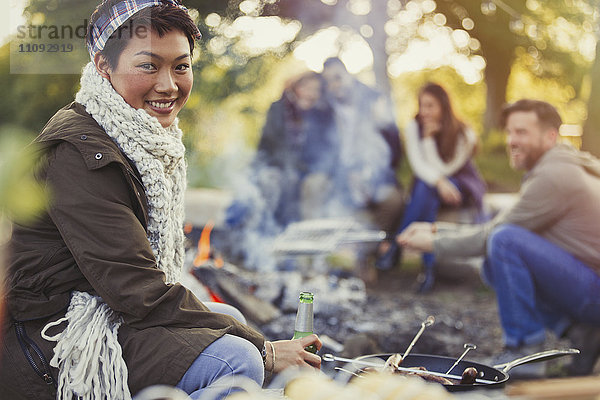 Portrait lächelnde Frau beim Biertrinken mit Freunden am Lagerfeuer