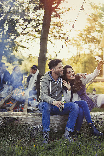 Paar posiert für Selfie mit Fotohandy am Lagerfeuer