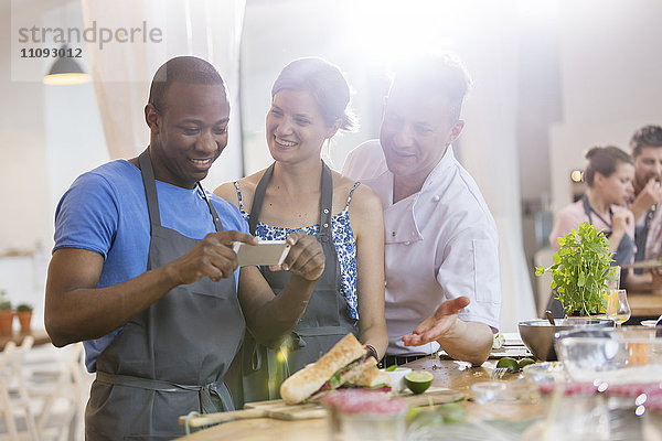 Mann fotografiert Essen in der Küche des Kochkurses