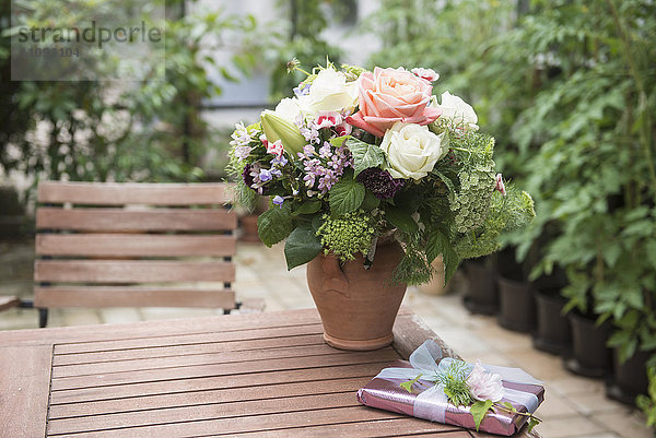 Geschenk mit Blumenstrauß auf Tisch im Garten  München  Bayern  Deutschland