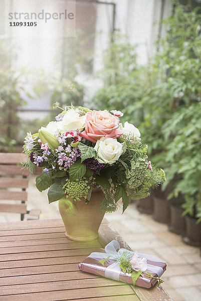 Geschenk mit Blumenstrauß auf Tisch im Garten  München  Bayern  Deutschland