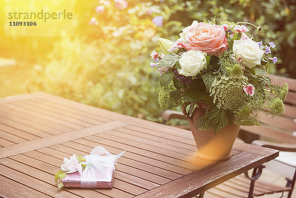 Geschenk mit Blumenstrauß auf Tisch im Garten  München  Bayern  Deutschland