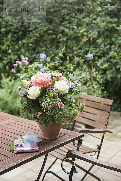 Geschenk mit Blumenstrauß auf Tisch im Garten  München  Bayern  Deutschland