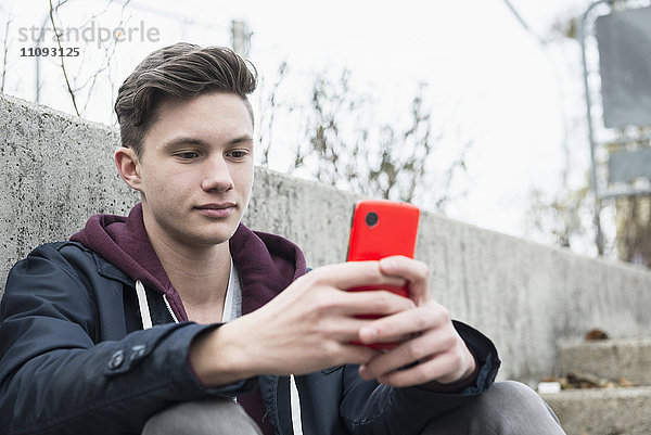 Junger Mann mit Textnachrichten auf einem Smartphone