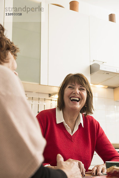 Zwei ältere Frauen reden und lachen in der Küche