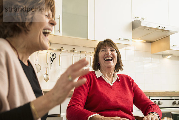 Zwei ältere Frauen reden und lachen in der Küche