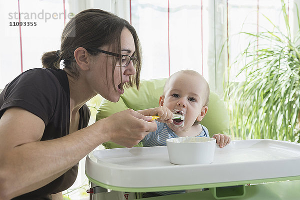 Mutter füttert ihren kleinen Jungen mit einem Löffel mit Babynahrung  München  Bayern  Deutschland