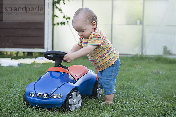 Kleiner Junge spielt mit seinem Spielzeugauto auf einer Wiese  München  Bayern  Deutschland