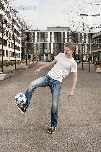 Jugendlicher spielt Fußball  indem er den Ball auf dem Fuß balanciert