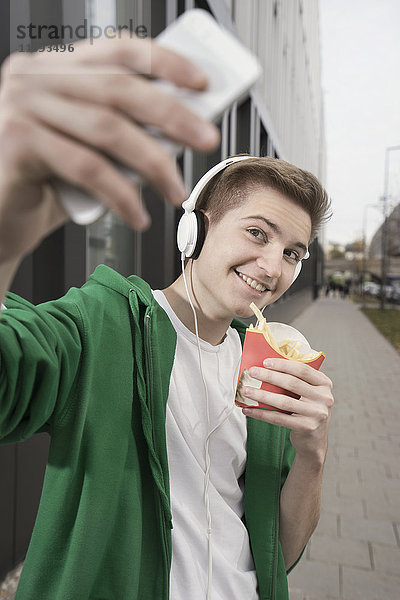 Glücklicher Teenager  der ein Selfie mit Pommes macht