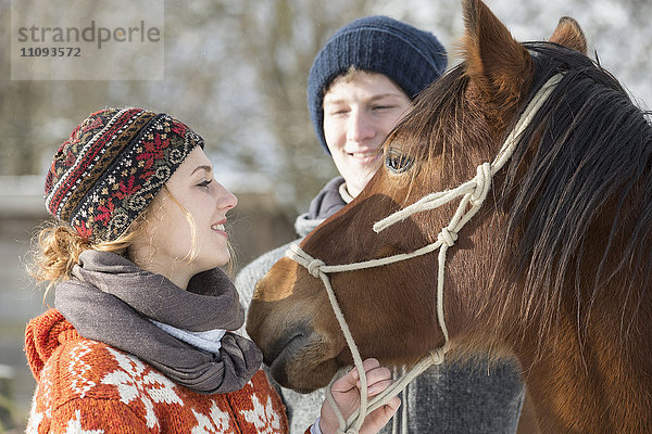 Junges Paar stehend mit Pferd in Scheune  Bayern  Deutschland