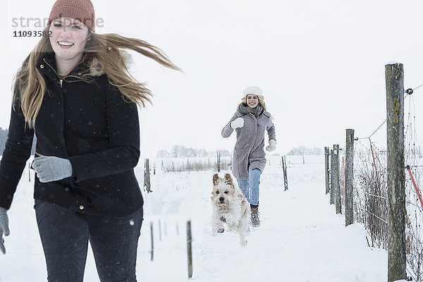 Teenager-Mädchen läuft mit Hund im Schneefeld  Bayern  Deutschland