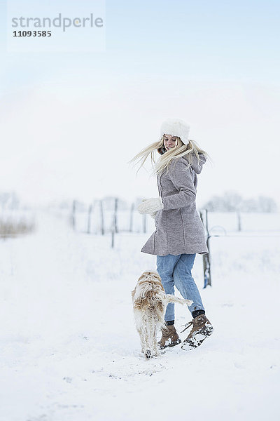 Teenager-Mädchen läuft mit ihrem Hund in verschneiter Landschaft  Bayern  Deutschland