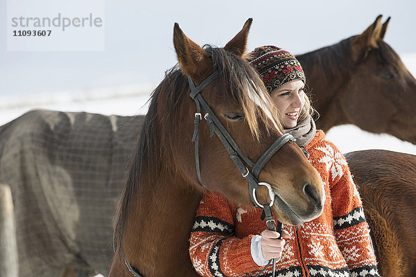 Junge Frau stehend mit Pferd auf dem Bauernhof  Bayern  Deutschland