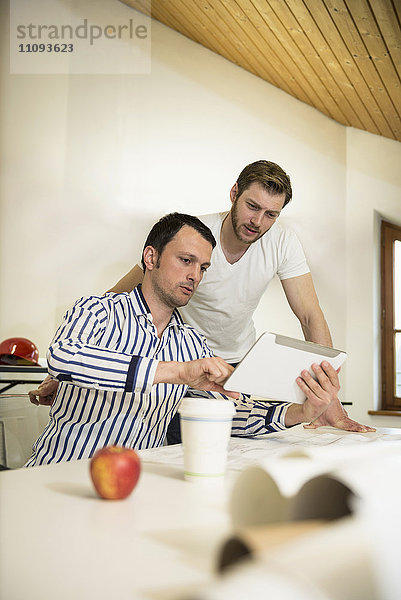 Architekten diskutieren über ein Projekt auf einem digitalen Tablet in einem Büro  Bayern  Deutschland