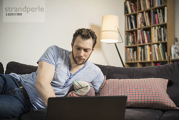 Mittelgroßer erwachsener Mann arbeitet an einem Laptop im Wohnzimmer  München  Bayern  Deutschland