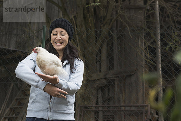 Bäuerin mit weißem Huhn und lächelndem Vogel auf dem Bauernhof