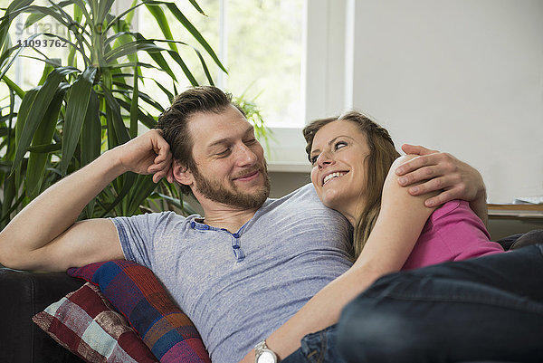 Paar  das sich auf dem Sofa im Wohnzimmer ausruht und sich gegenseitig anschaut  München  Bayern  Deutschland