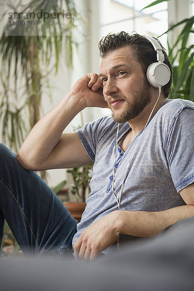 Mittlerer erwachsener Mann hört Musik im Wohnzimmer  München  Bayern  Deutschland