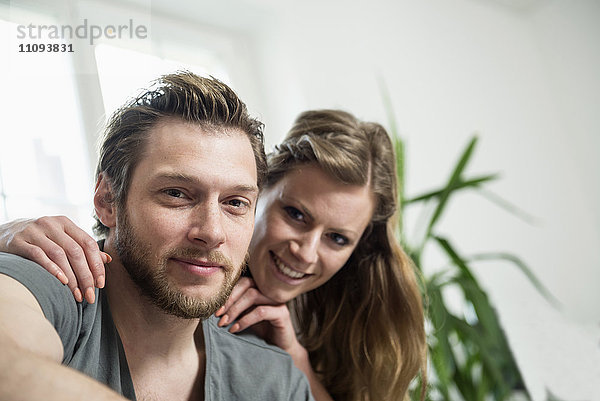Porträt eines lächelnden Paares in einem Wohnzimmer  München  Bayern  Deutschland