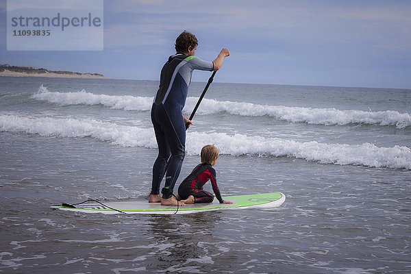Vater mit seinem Sohn beim Paddeln auf dem Meer