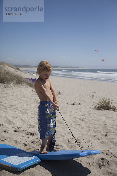 Kleines Kind zieht Bodyboard am Strand
