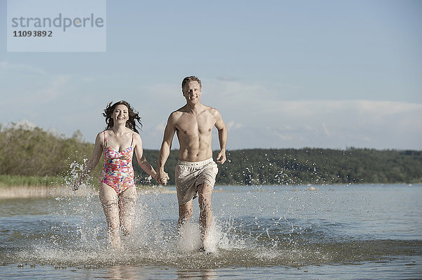 Älteres Paar läuft durch das Wasser in einem See  Bayern  Deutschland