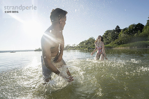 Reifes Paar bespritzt sich gegenseitig mit Wasser am See  Bayern  Deutschland