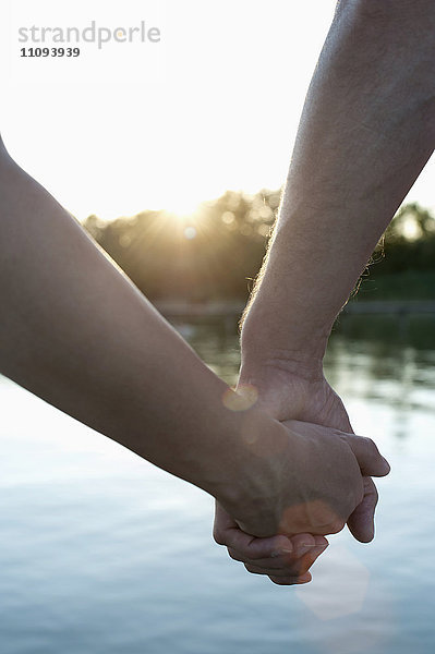 Nahaufnahme eines verliebten Paares  das sich bei Sonnenuntergang die Hände hält  Bayern  Deutschland