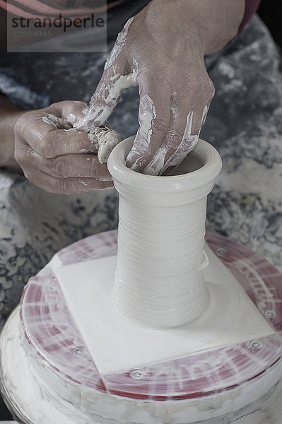Nahaufnahme einer Töpferin beim Formen von Ton mit einem Reinigungsschwamm in einer Werkstatt  Bayern  Deutschland