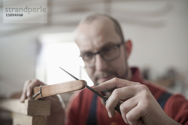Männlicher Bogenbauer feilt die Spitzen eines Bogens in der Werkstatt  Bayern  Deutschland