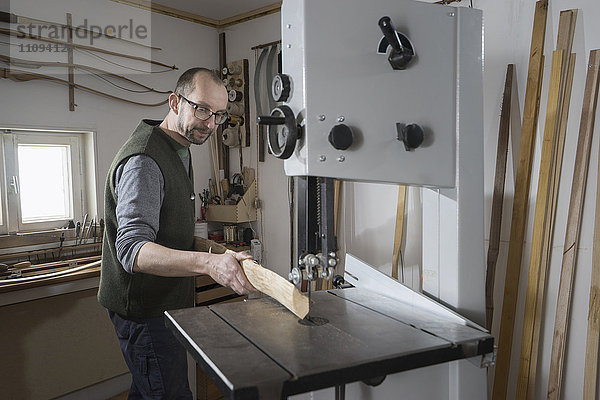 Männlicher Bogenbauer beim Sägen von Holz mit einer Bandsäge  Bayern  Deutschland