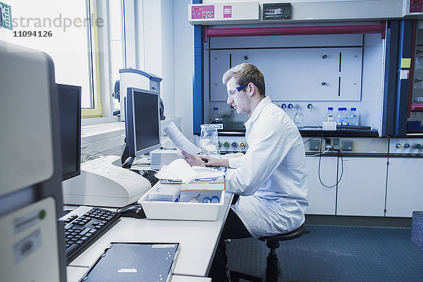 Junger männlicher Wissenschaftler bei der Arbeit in einem Apothekenlabor