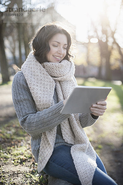 Ältere Frau benutzt digitales Tablet im Park und lächelt  Bayern  Deutschland