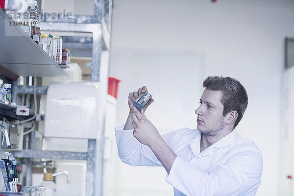 Junger männlicher Wissenschaftler bei der Arbeit in einem Apothekenlabor