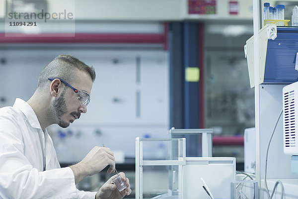 Junger männlicher Wissenschaftler bei der Arbeit in einem Apothekenlabor