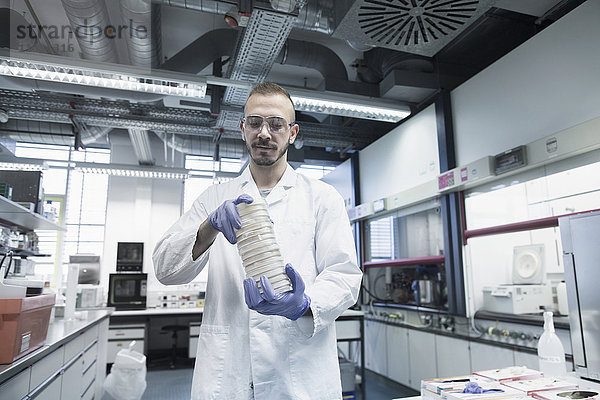 Wissenschaftlerin hält einen Stapel Petrischalen in einem Apothekenlabor