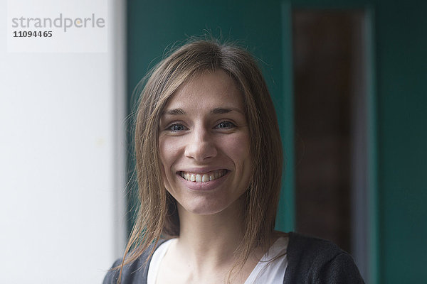 Porträt einer jungen Frau  die vor einer Haustür lächelt