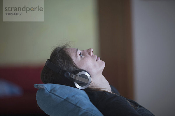 Junge Frau entspannt sich und hört zu Hause Musik