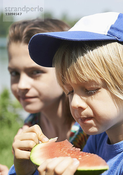 Kinder genießen ein Stück Wassermelone beim Picknick  München  Bayern  Deutschland