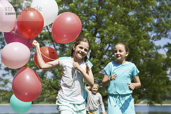 Mädchen laufen im Park mit Luftballons  Karlsfelder See  München  Bayern  Deutschland