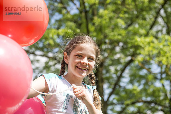 Porträt eines lächelnden Mädchens mit roten Luftballons  München  Bayern  Deutschland